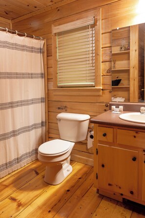 A wooden cabin bathroom with a toilet, a sink, and a window with blinds. - Fern Cabin - Hot Tub & Mountain Views - Dog Friendly! (Blue Ridge)