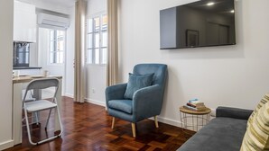 Un salon moderne avec un canapé gris, un fauteuil bleu et une petite table ronde sur laquelle sont posés des livres.