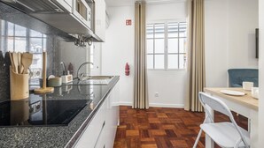 Une cuisine moderne avec un plan de travail noir, un revêtement de sol en bois et un coin repas comprenant une table et des chaises.