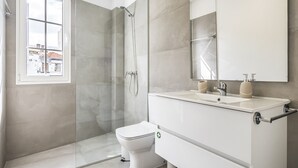 Un baño moderno con cabina de ducha de vidrio, inodoro y tocador con espejo.