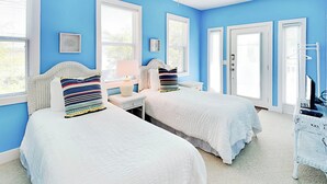 A bedroom with two beds, a desk, and a chair. - Mercy Me by Tybee Vacation Rentals (Tybee Island)