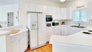 A modern kitchen with white cabinetry, a built-in microwave, a toaster, and a sink. - Mercy Me by Tybee Vacation Rentals (Tybee Island)