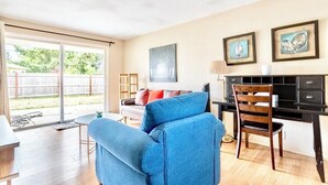 A living room with a blue sofa, a wooden chair, a desk with a lamp, and artwork on the wall. - Private Getaway Near Beaches & Downtown Tacoma! (Tacoma)