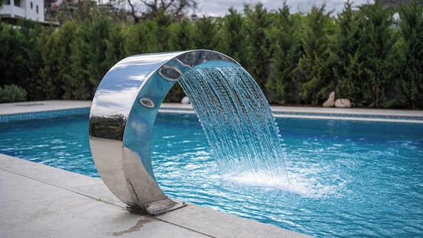 Une piscine moderne dotée d’un élément aquatique original, aux lignes courbes.