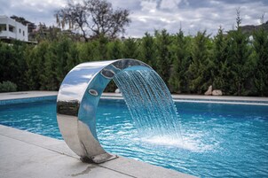 Una piscina moderna con una llamativa fuente de agua curva.