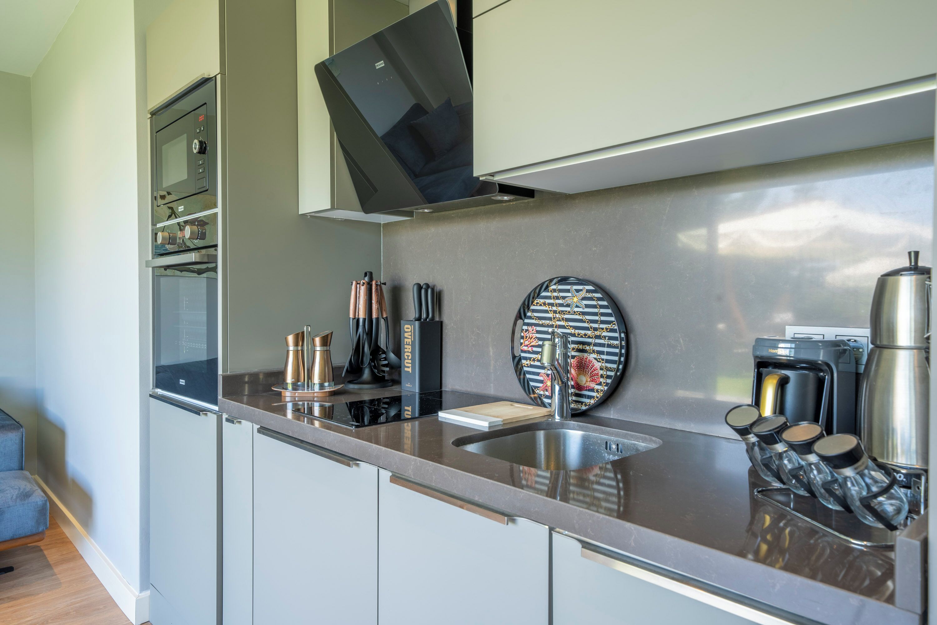 A modern kitchen with a built-in microwave, coffee maker, and a stainless steel sink.