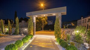 Une entrée bien éclairée, agrémentée d’une arche en pierre, d’un chemin pavé et de haies soigneusement taillées.