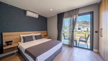 Quarto de hotel moderno com uma cama grande, cabeceira de madeira, mesa de cabeceira e vista para a varanda externa.