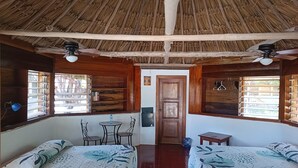 Una stanza con due letti, un tavolino, sedie, un ventilatore a soffitto e una porta che dà su un'altra stanza.