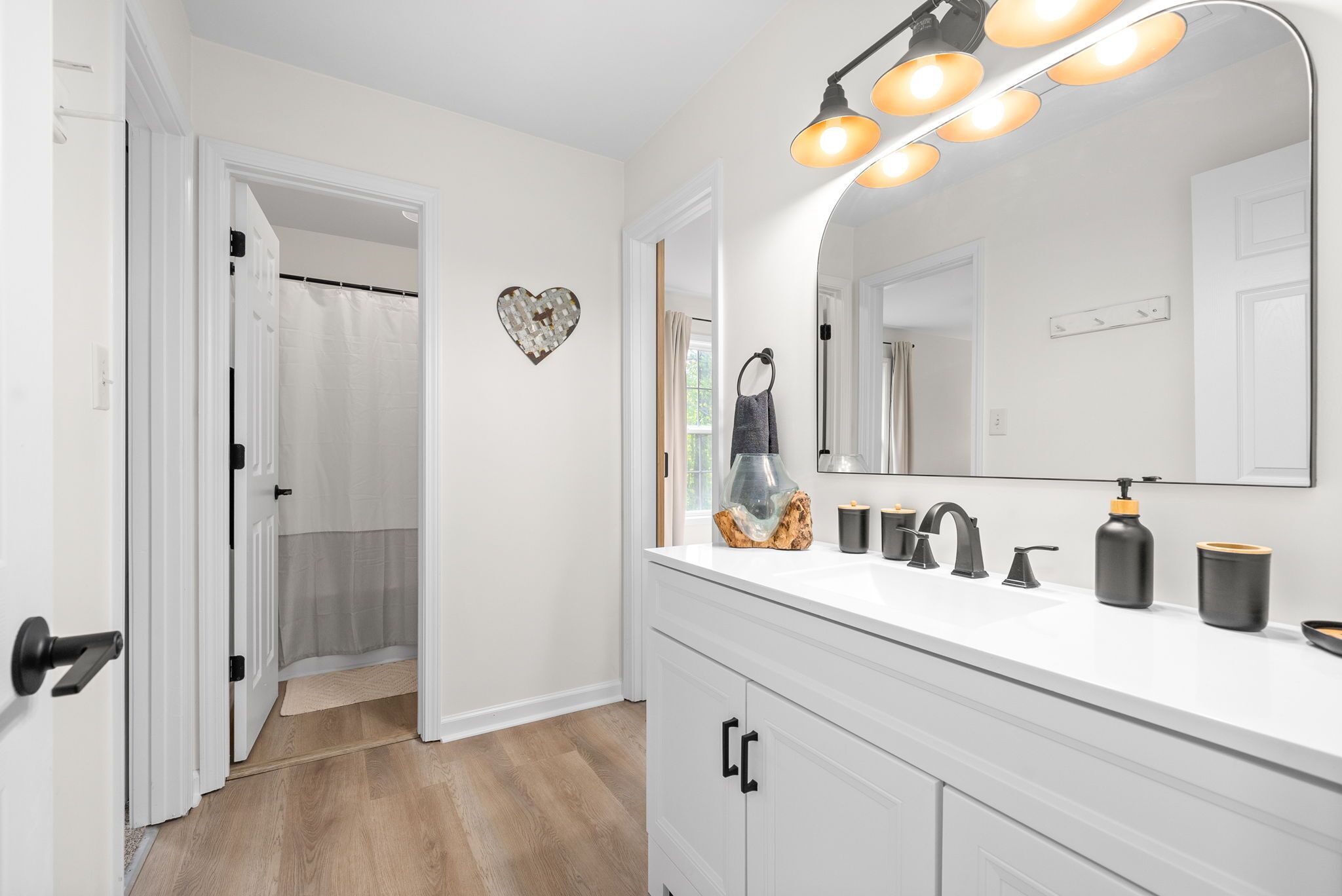 A bathroom with a white vanity, a large mirror, and a shower curtain.