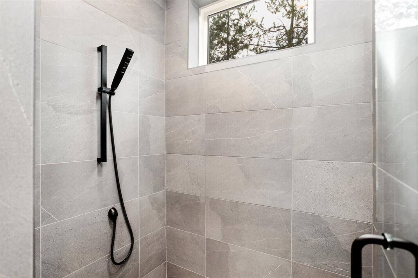 A shower area with a window, tiled walls, and a showerhead.