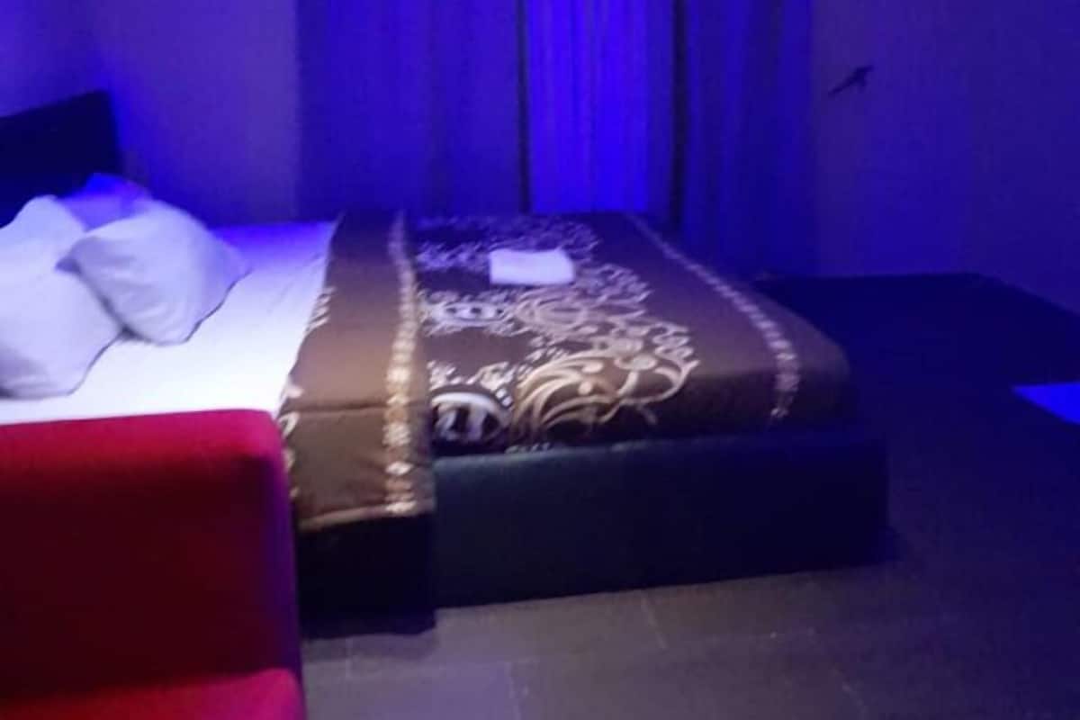 Een kamer met een bed, een rode stoel en een klein tafeltje.