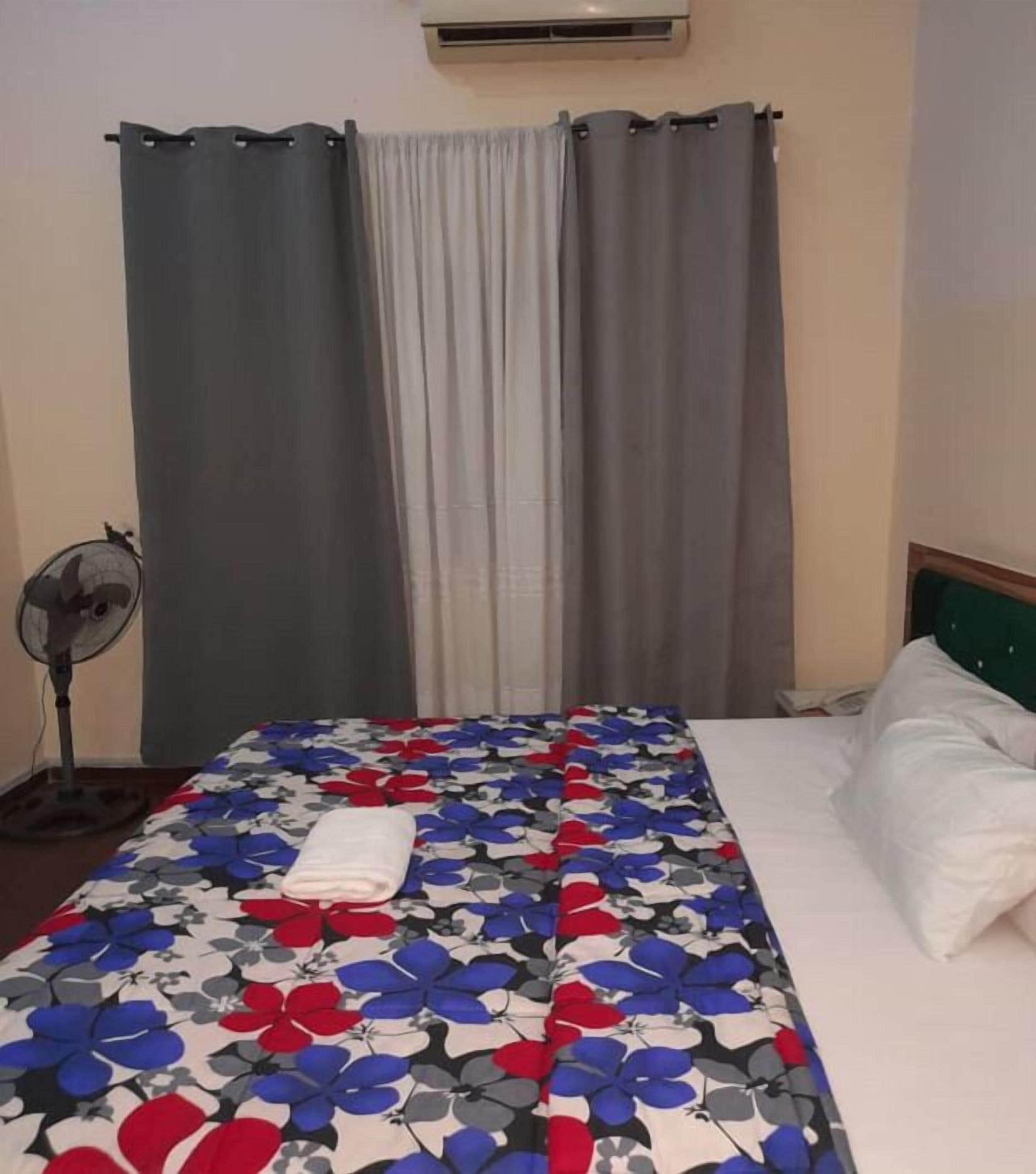 Ein Hotelzimmer mit Bett, Ventilator und Vorhängen.
