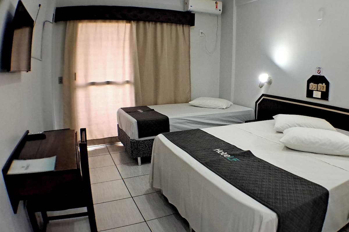 Habitación de hotel con dos camas individuales, un escritorio y una silla.