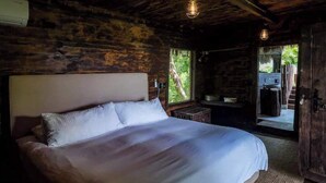 Une chambre avec un grand lit, des murs en bois et une vue sur l’extérieur.