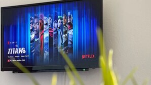 A flat-screen TV mounted on a wall displaying the Netflix series 'Titans'. - Grupo Morgado (Tavira)