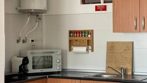 A kitchen with a microwave, toaster, sink, and wooden cabinets. - Grupo Morgado (Tavira)