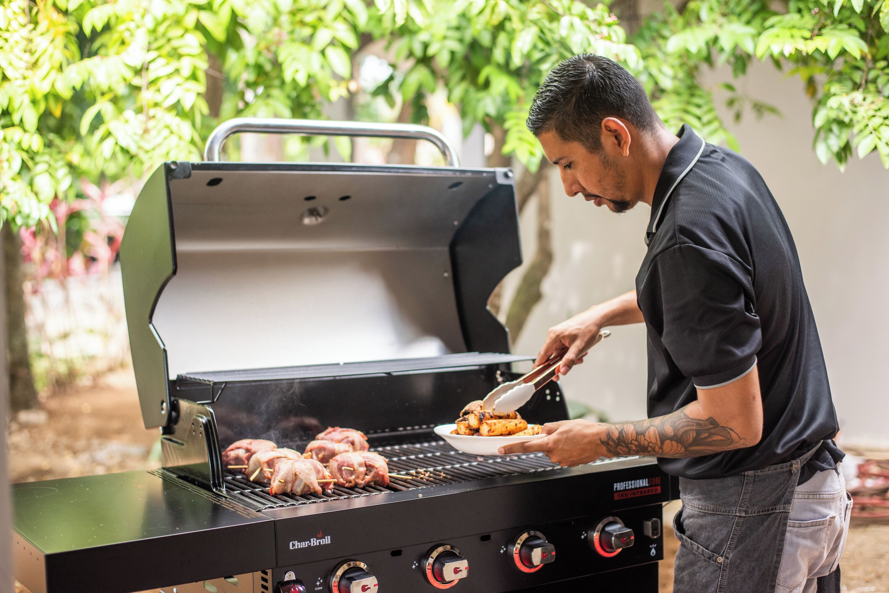 A man grilling meat on an outdoor grill with a digital control panel.