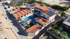 A large, multi-story building with a swimming pool, solar panels on the roof, and a parking area. - Hotel Pousada Canoa Quebrada (Aracati)
