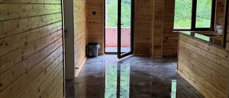 Un interior de madera con piso pulido, una puerta que da al exterior y una ventana con vistas a follaje.