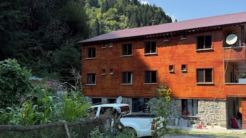 A two-story wooden building with a red roof, a satellite dish, and a stone foundation.