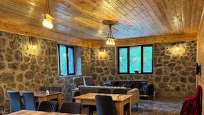 Una habitación amplia con pared de piedra, techo de madera y ventanas grandes.
