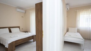 A hotel room with two beds, a wooden headboard, white bedding, and a large window with sheer curtains. - Central Seaview Apartment by PikHost (Vlorë)
