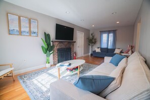 Un salon avec une cheminée, un canapé, une table basse et un téléviseur fixé au mur.