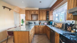 Une cuisine avec des meubles en bois, un plan de travail en granit, un four à micro-ondes, une cuisinière et un évier.