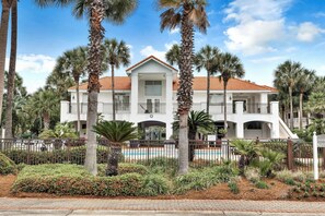 A two-story building with a red-tiled roof, surrounded by palm trees and a swimming pool. - Casa Mar (Destin)