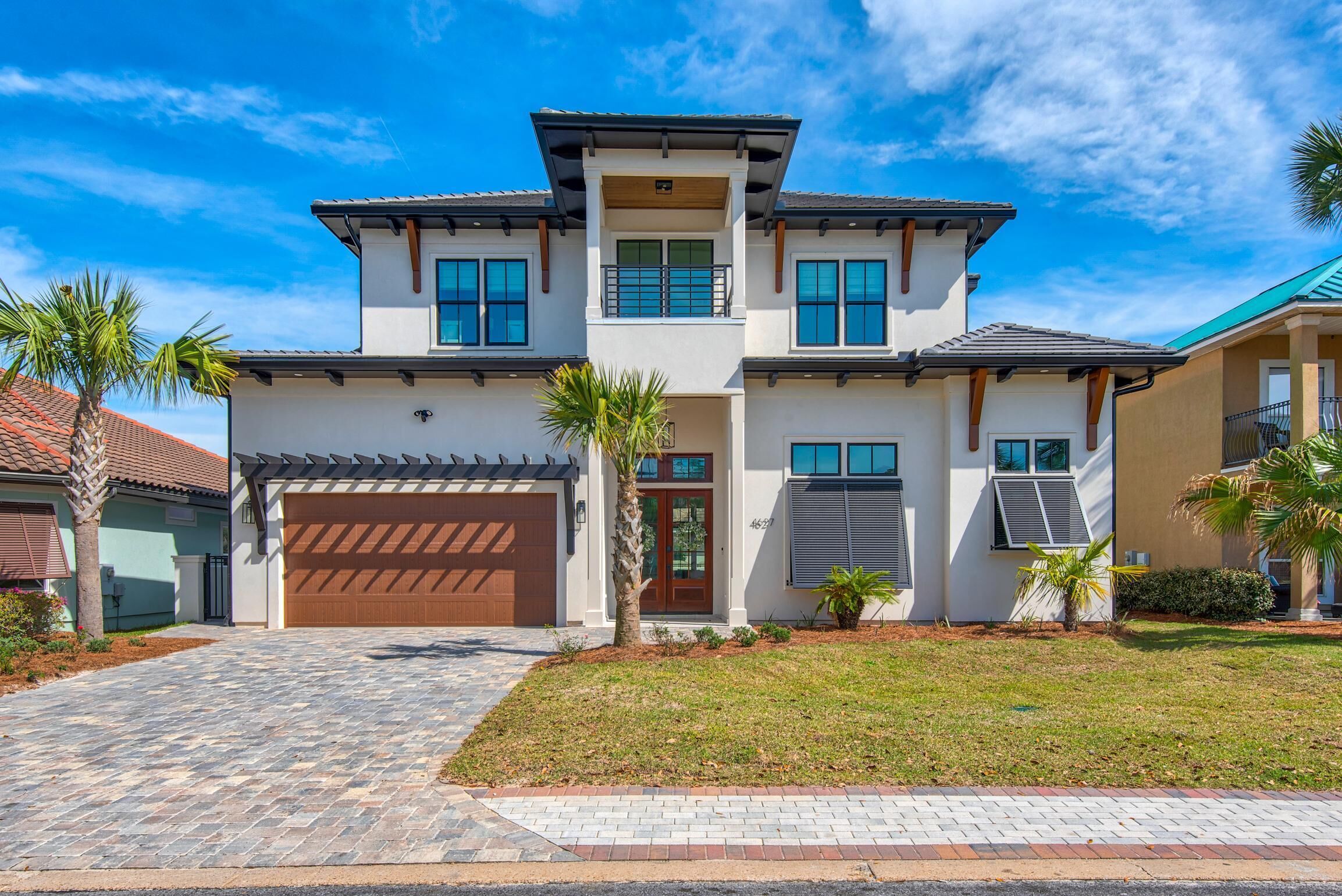 A two-story house with a garage, a covered driveway, and a well-maintained lawn.