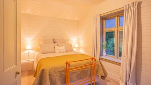 Ein Schlafzimmer mit einem Bett, Nachttischen, einem Fenster mit Vorhängen und einer Holzleiter.