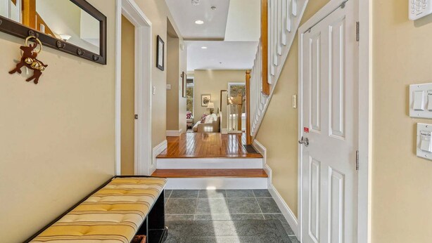 A hallway with a bench, doors, a staircase, and a mirror. - Condo with Pool, Newton Village, Pet-Friendly (Quechee)