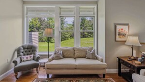 A living room with a sofa, armchair, and a lamp on a side table. - Condo with Pool, Newton Village, Pet-Friendly (Quechee)