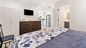 Une chambre à coucher comprenant un lit, une commode, un téléviseur fixé au mur et un ventilateur de plafond.