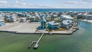 An aerial view of a coastal residential area with houses, a pier, and a beach. - Bora Bora Beach House (Navarre)