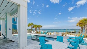 A poolside area with a view of the ocean, outdoor seating, and a sign indicating a swimming area. - Bora Bora Beach House (Navarre)