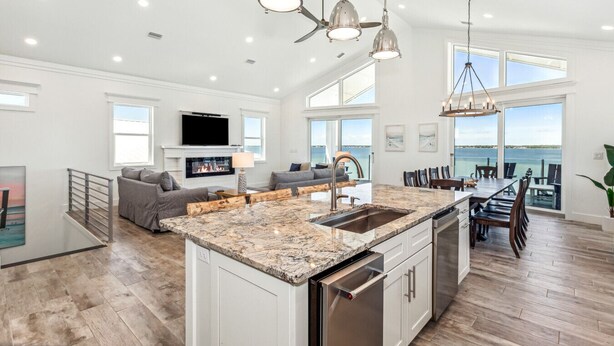 A spacious kitchen with a large island, modern pendant lights, and a view of the ocean. - Bora Bora Beach House (Navarre)