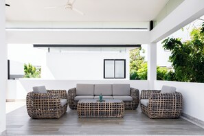A modern outdoor seating area with wicker furniture and a grey sofa, featuring a ceiling fan and a view of greenery. - Laguna Park 4 Bedrooms Villa by NLA (Choeng Thale)