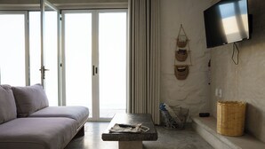 Un salón moderno con un sofá, una mesa de piedra, cestas de mimbre y un televisor montado en la pared.