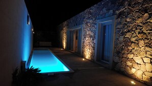 Un edificio de piedra con zona de piscina por la noche.