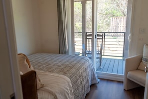 Ein Schlafzimmer mit einem Bett, einem Sessel und Blick auf eine Terrass.