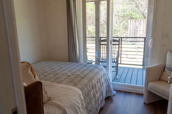 Un dormitorio con cama, una silla y vistas a una terraza.