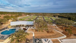 A resort with a swimming pool, outdoor seating, and a large building with a flat roof.