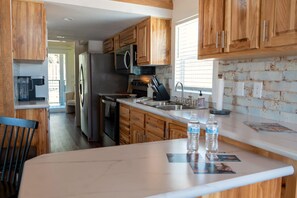 Una cocina con armarios de madera, electrodomésticos de acero inoxidable y encimera de mármol.
