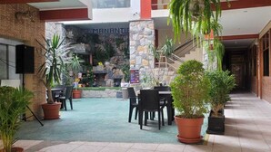 A courtyard with a stone wall, potted plants, and outdoor seating. - Hotel Manantial (Pachangara)