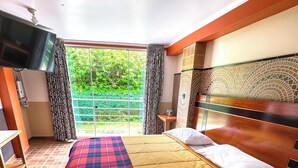 A hotel room with a bed, a TV, a desk, and a view of greenery outside. - Hotel Manantial (Pachangara)