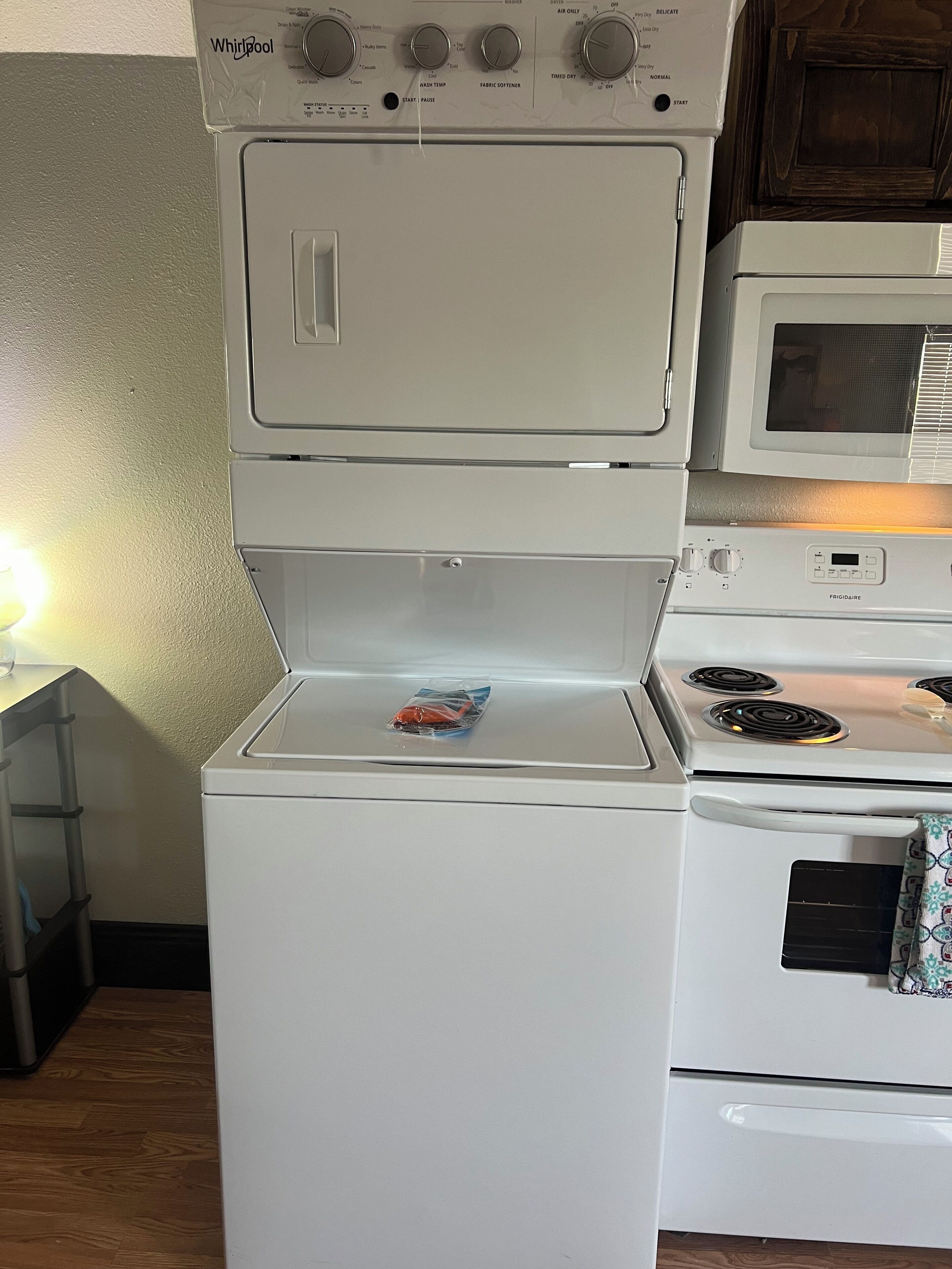 A kitchen with a stacked washer and dryer, a microwave, and an oven.
