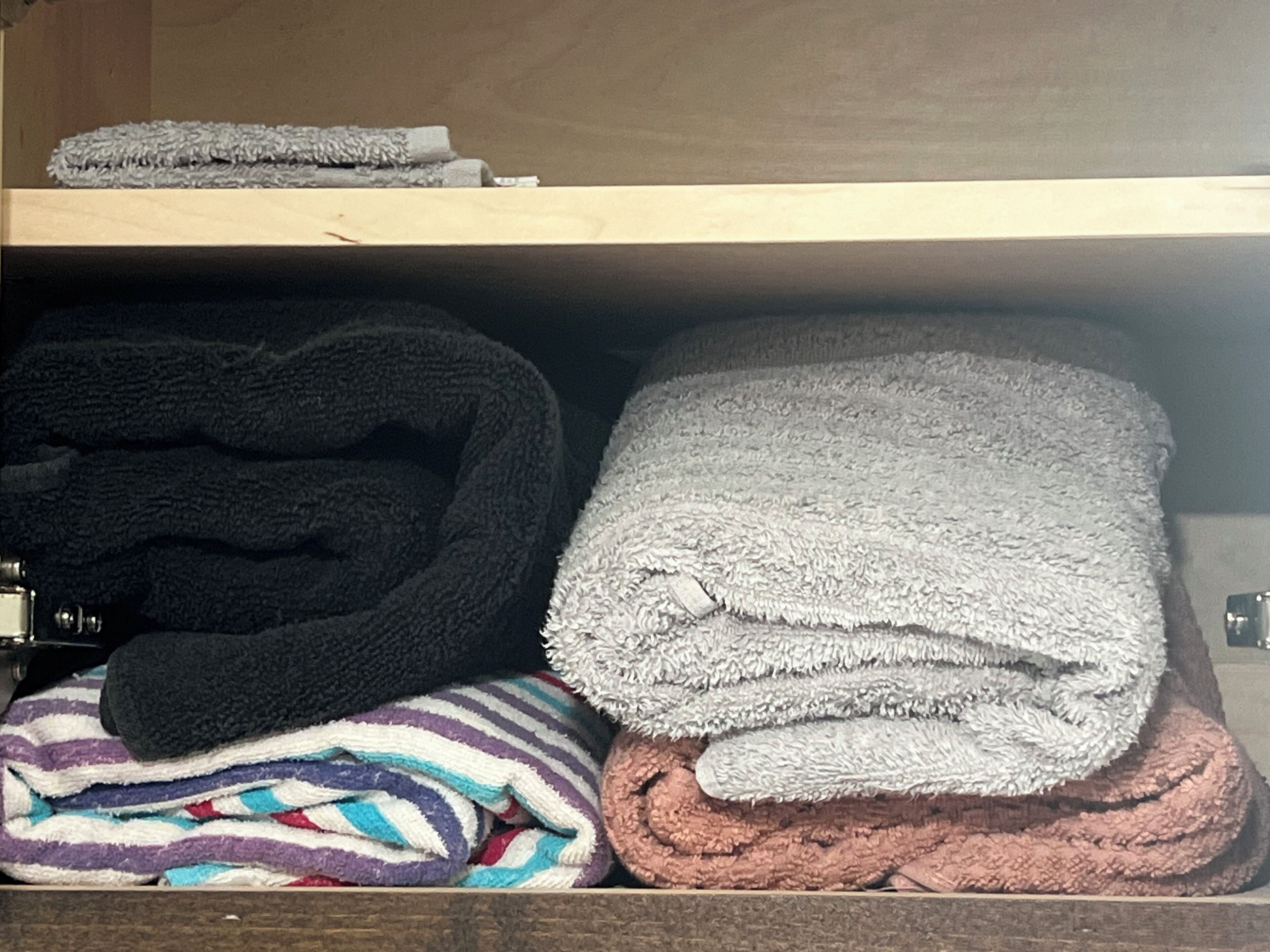 A storage area with neatly folded towels in various colors and patterns.