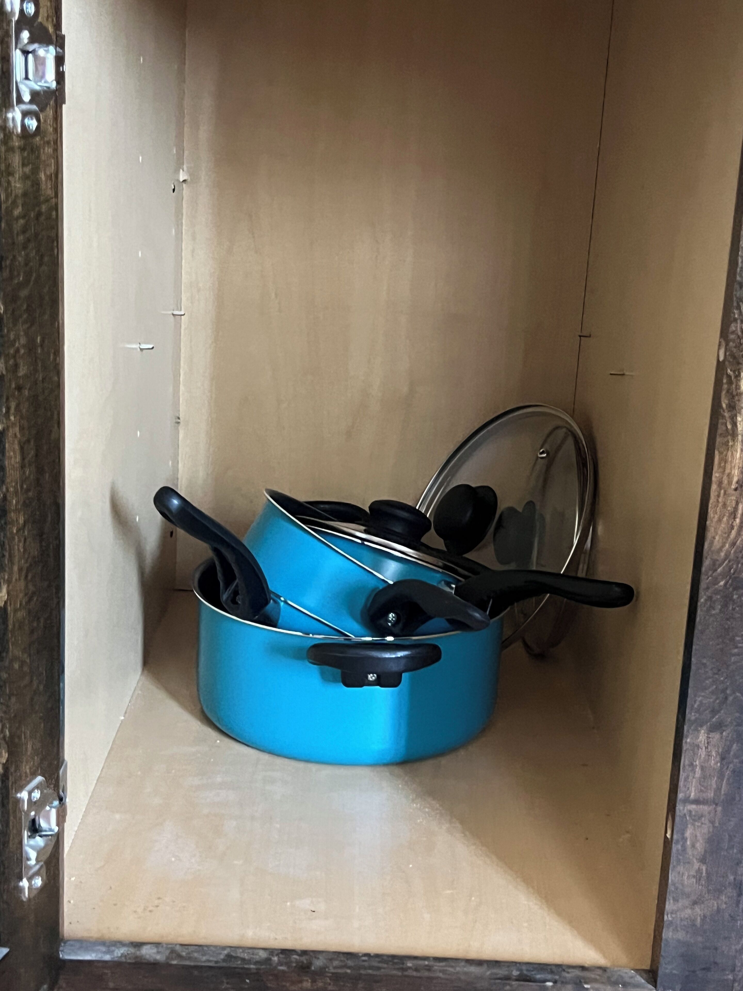 Un pot bleu avec un couvercle et des anses, posé sur une étagère à l’intérieur d’un meuble.